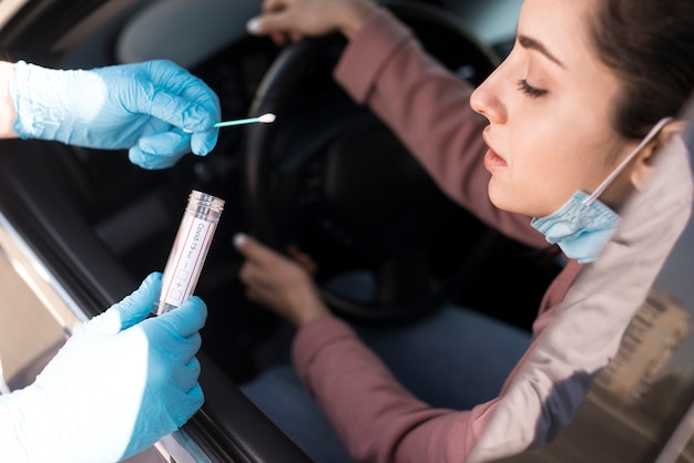 Persona probando a una mujer en el auto por coronavirus Foto gratis