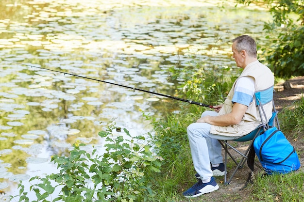 Pescador pescando en la orilla del lago | Foto Premium