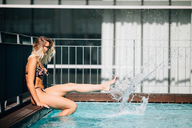 Pie femenino en agua azul. pies chapoteando en la piscina. piernas de mujeres jugando y retozando con agua en una piscina. Foto gratis