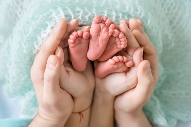Piernas Del Bebe En Manos De Papa Y Mama Sobre Un Fondo Azul Concepto De Familia Foto Premium