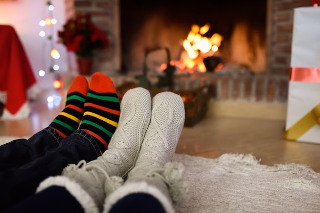 Pies con calcetines de navidad cerca de una chimenea | Descargar Fotos