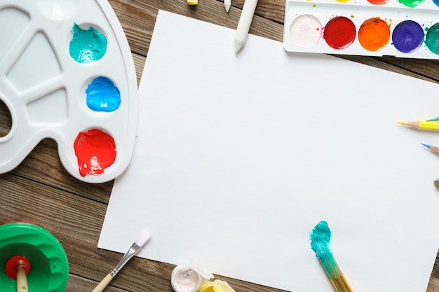 Pinturas De Acuarelas Y Pinceles Con Papel Blanco En Blanco Sobre Mesa