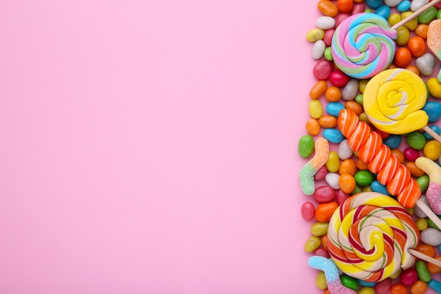 Piruletas de colores y dulces redondos de diferentes colores sobre fondo rosa Foto Premium
