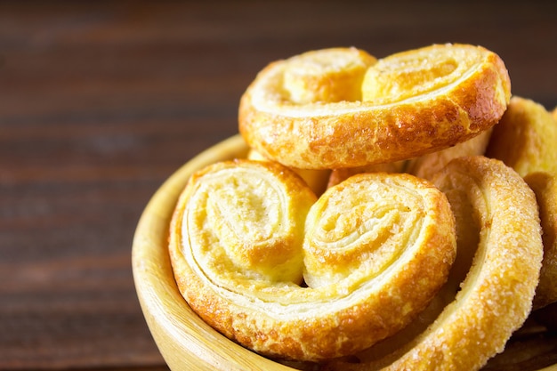 Pretzels dulces hechos de hojaldre en un recipiente en una mesa de madera Foto Premium