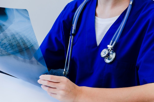 Primer plano de una doctora en uniforme azul examinando la radiografía Foto gratis