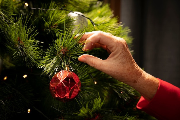 Primer plano de la mano configurando el árbol de navidad Foto gratis