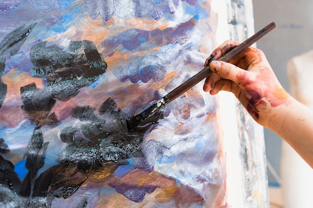 Primer plano de la mano del hombre pintura sobre lienzo con pincel ...