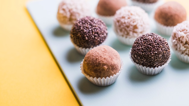 Primer plano de trufas de chocolate en bandeja blanca sobre fondo amarillo Foto gratis