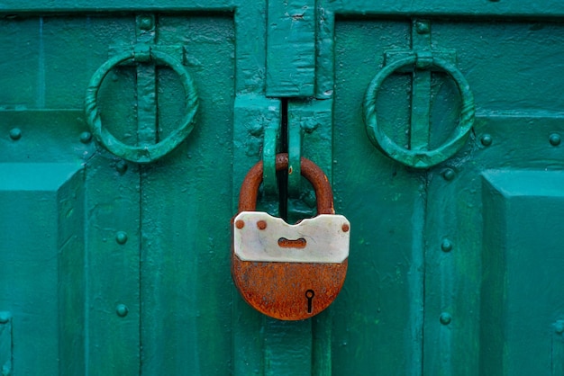 La puerta de metal está cerrada con candado candado oxidado en la