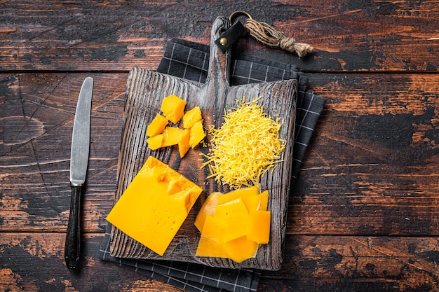 Queso Cheddar Rallado Y Cortado En Cubitos Sobre Una Tabla De Cortar De