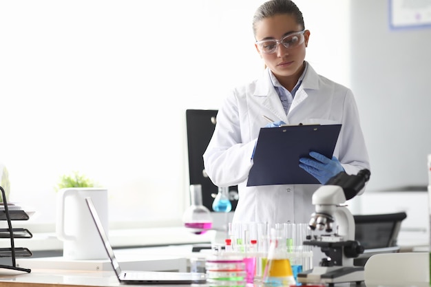 Químico científico de la mujer escribiendo en documentos en laboratorio ...