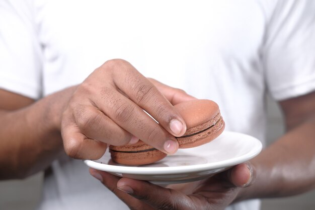 Recoger A Mano Macarrones De Color Chocolate De Un Plato Foto Premium