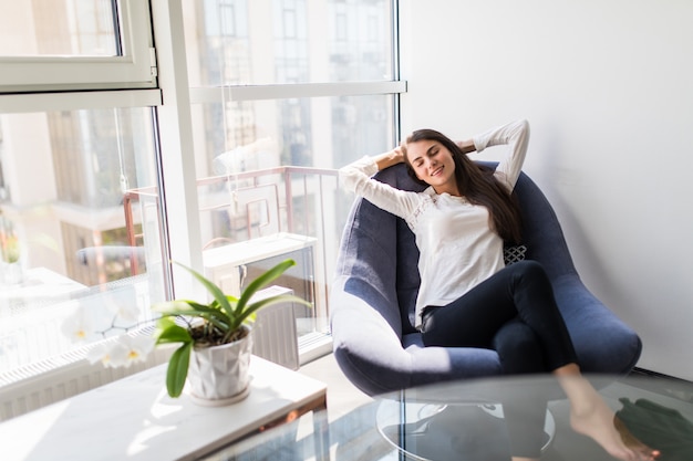 Relajante mujer sentada cómoda en el sillón del sofá en casa Foto gratis
