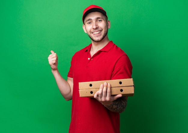 Repartidor Joven Sonriente Vistiendo Uniforme Con Gorra Sosteniendo Cajas De Pizza Mostrando El 1753