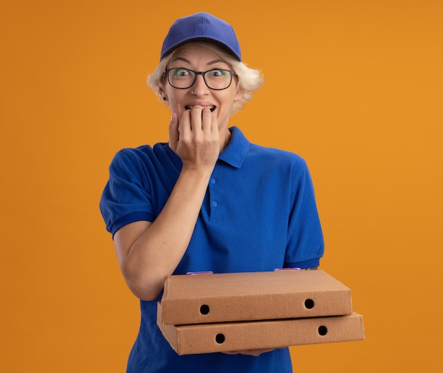 Repartidor Joven En Uniforme Azul Y Gorra Con Gafas Sosteniendo Cajas De Pizza Estresado Y 9917