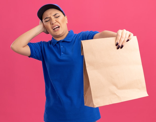 Repartidor Joven En Uniforme Azul Y Gorra Sosteniendo El Paquete De