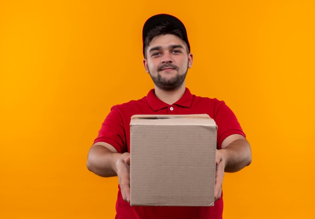 Repartidor Joven En Uniforme Rojo Y Gorra Con Paquete De Caja Sonriendo Confiado Foto Gratis 4235