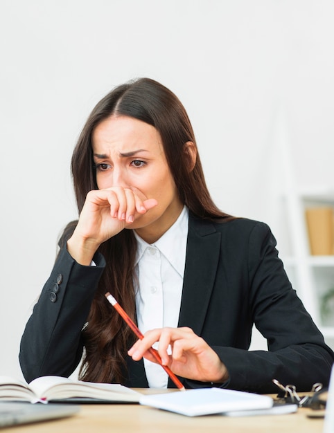 Retrato de la empresaria joven triste que sostiene el lápiz rojo en su mano que llora Foto gratis