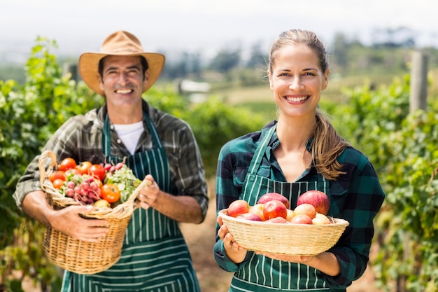 Retrato de la feliz pareja de agricultores con cestas de frutas y verduras Foto Premium 