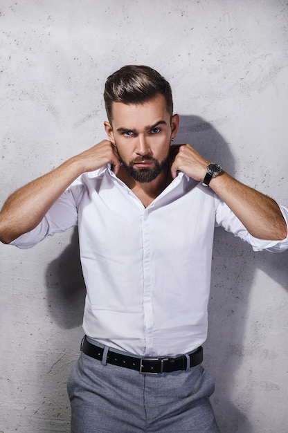 Retrato de hombre guapo con barba con camisa blanca está posando contra