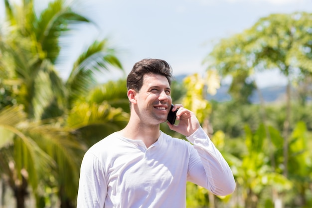 Retrato del hombre sonriente feliz que hace llamada telefónica sobre el