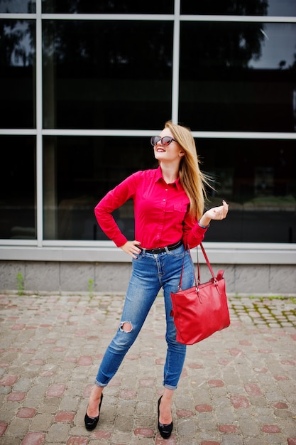 Retrato De Una Joven Fabulosa En Blusa Roja Y Jeans Posando Con Su Bolso Y Gafas De Sol Fuera Del Centro Comercial Foto Premium