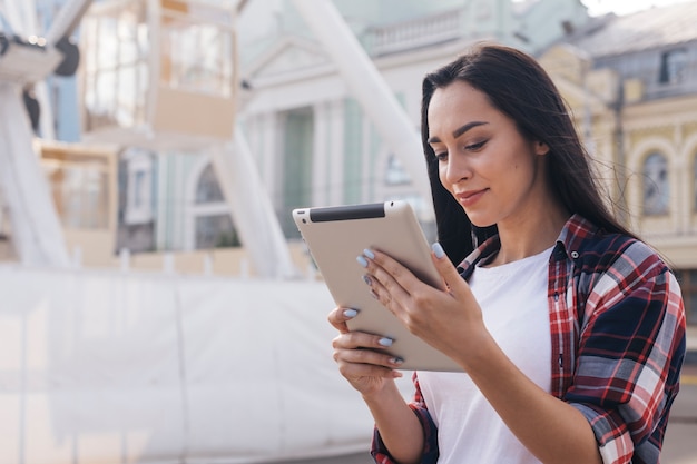 Retrato de joven mujer bonita con tableta digital al aire libre Foto gratis