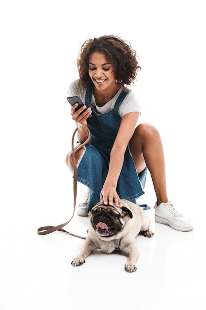 Retrato de mujer feliz con teléfono celular y en cuclillas mientras se