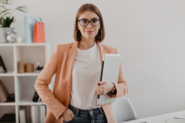 Retrato De Mujer De Negocios Exitosa Con Gafas Y Chaqueta Ligera Sonriendo Contra La Oficina 