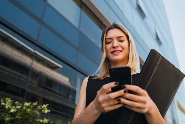 Retrato De Mujer De Negocios Joven Que Usa Su Teléfono Móvil Mientras Está De Pie Fuera De Los