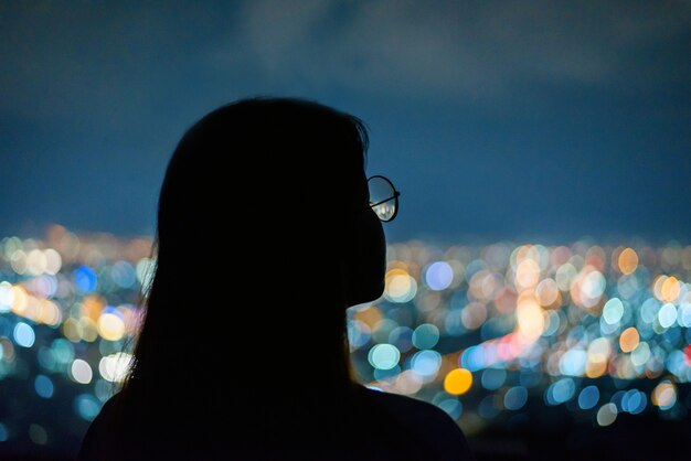 Retrato de mujer de silueta en bokeh de luz nocturna de la ciudad, chiang mai, tailandia Foto Premium