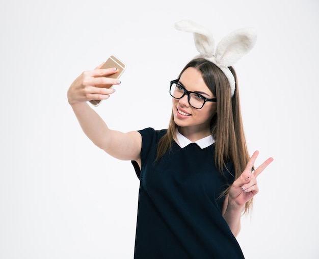 Retrato de una niña sonriente con orejas de conejo haciendo foto selfie