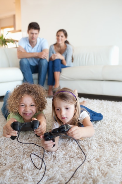 Retrato de niños jugando videojuegos mientras sus padres miran. | Descargar Fotos premium