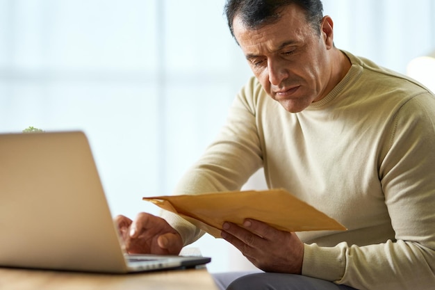 Retrato De Ocupado Empresario Latino De Mediana Edad Mirando El Sobre