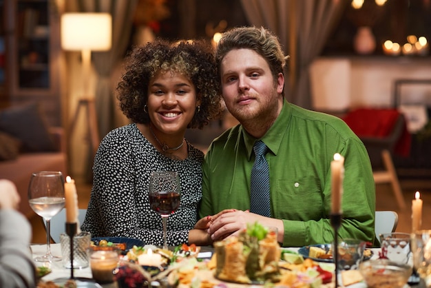 Retrato de pareja joven multiétnica sonriendo a la cámara mientras