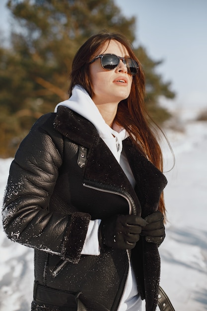 Retrato de primer plano de mujer con chaqueta negra. mujer de pie en un  bosque en día de nieve. | Foto Gratis
