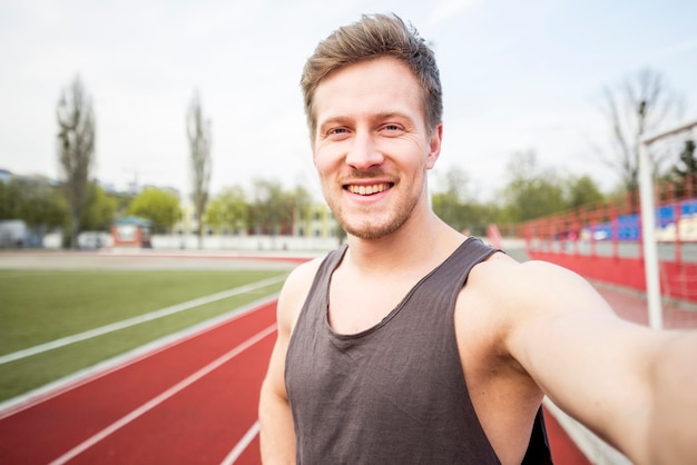 Retrato de sonriente atleta masculino hablando selfie en teléfono móvil Foto gratis