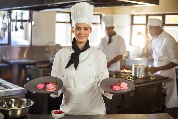 Retrato De Sonriente Mujer Chef Presentando Platos De Postre Foto Premium