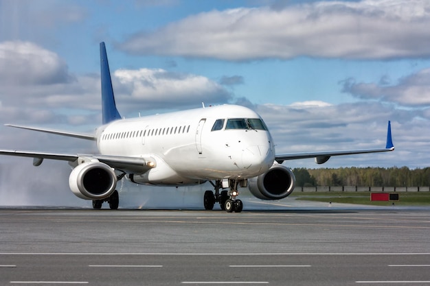 Rodaje de un avión de pasajeros blanco después de pasar por un arco de