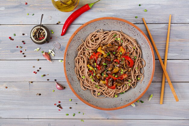 Salteado de corazones de pollo pimentón cebolla y fideos de trigo