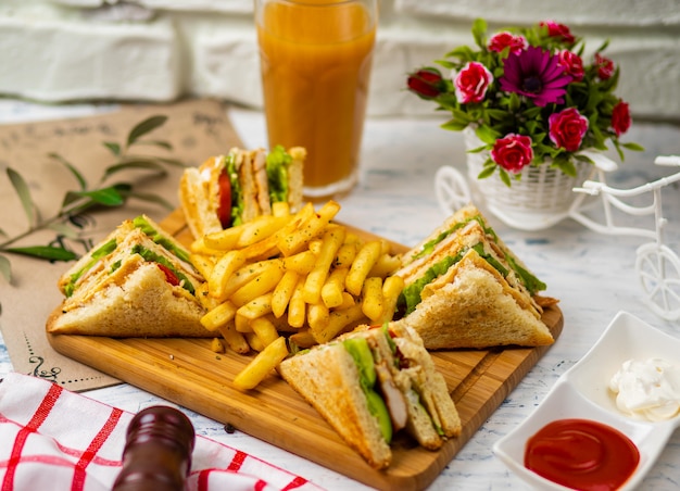 Sándwich club servido con papas fritas y refrescos, mayonesa, salsa de tomate Foto gratis