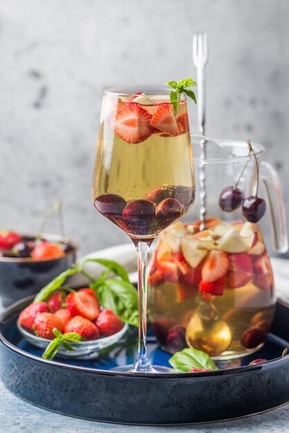 Sangría de vino blanco o ponche con frutos rojos y hielo en copa y