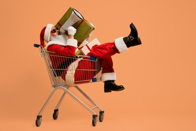 Santa gritando en megáfono mientras está sentado en el carrito de compras Foto Premium