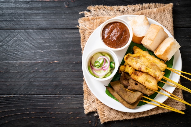 Satay De Cerdo Con Su Salsa De Man Y Encurtidos Que Son Rodajas De