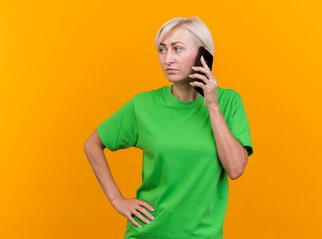 Segura mujer eslava rubia de mediana edad hablando por teléfono