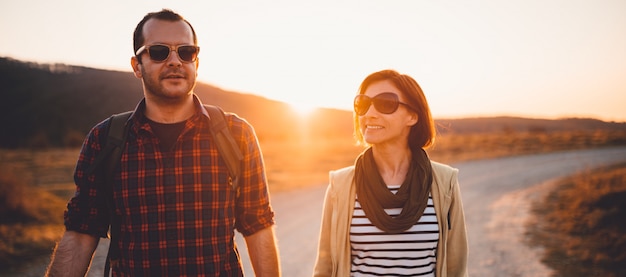 Senderismo feliz pareja en un camino de tierra durante el atardecer Foto Premium