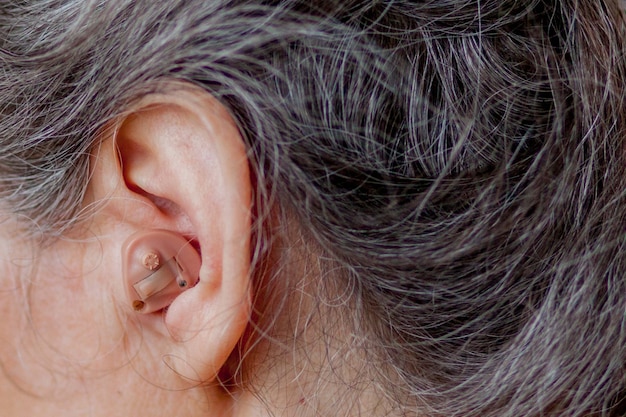 Senior mujer insertando audífono en sus oídos Foto Premium 