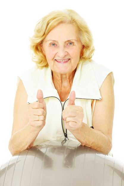 Una señora mayor feliz haciendo ejercicio con una pelota sobre fondo