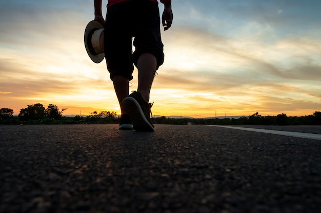 Silueta de un hombre caminando por la carretera en el momento de la puesta del sol | Foto Premium