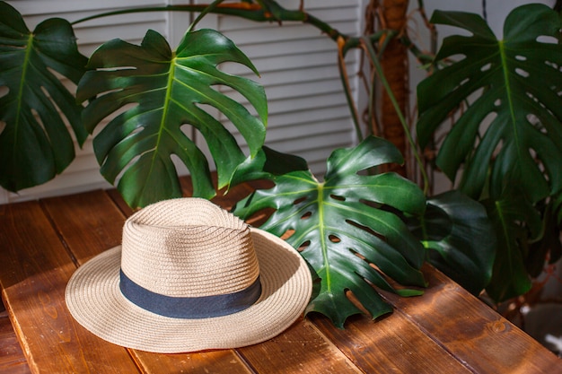 Un Sombrero De Paja Descansa Sobre Una Mesa De Madera Junto A Las Hojas Del Monstruo Un